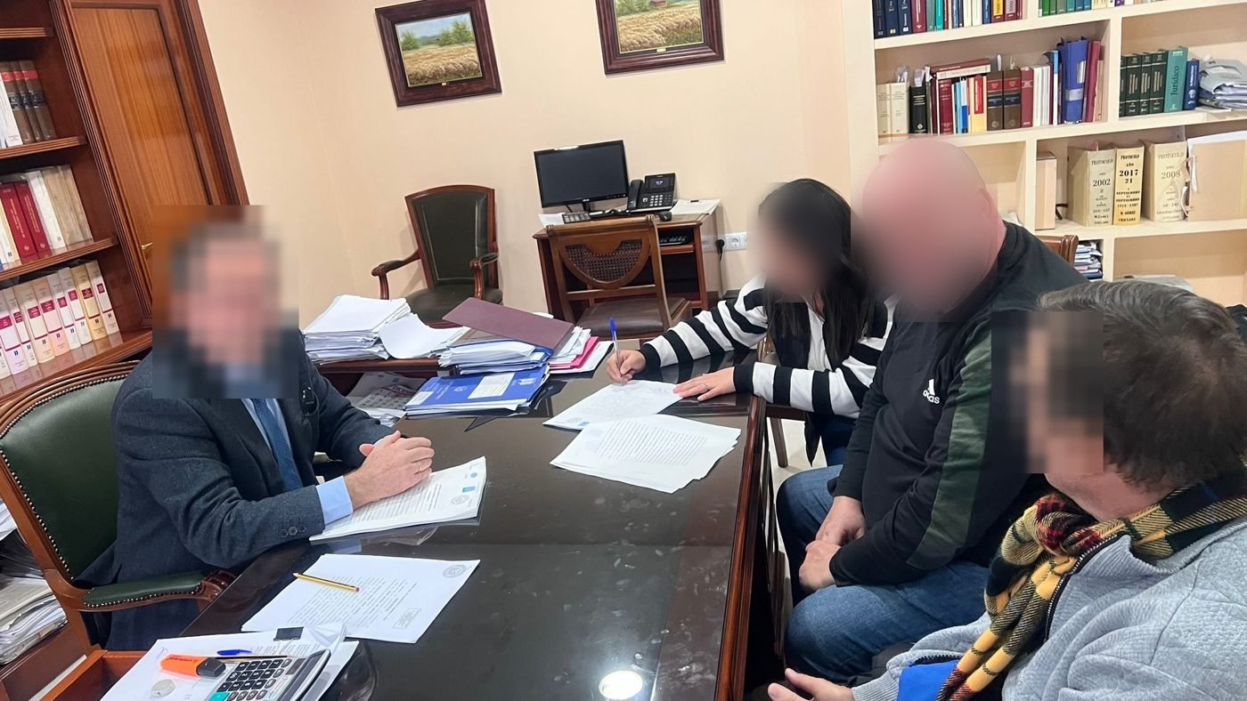 Clientes firmando las escrituras en la mesa del notario